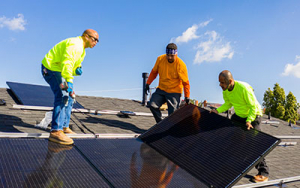 Team of workers installing solar panels on a residential rooftop in California