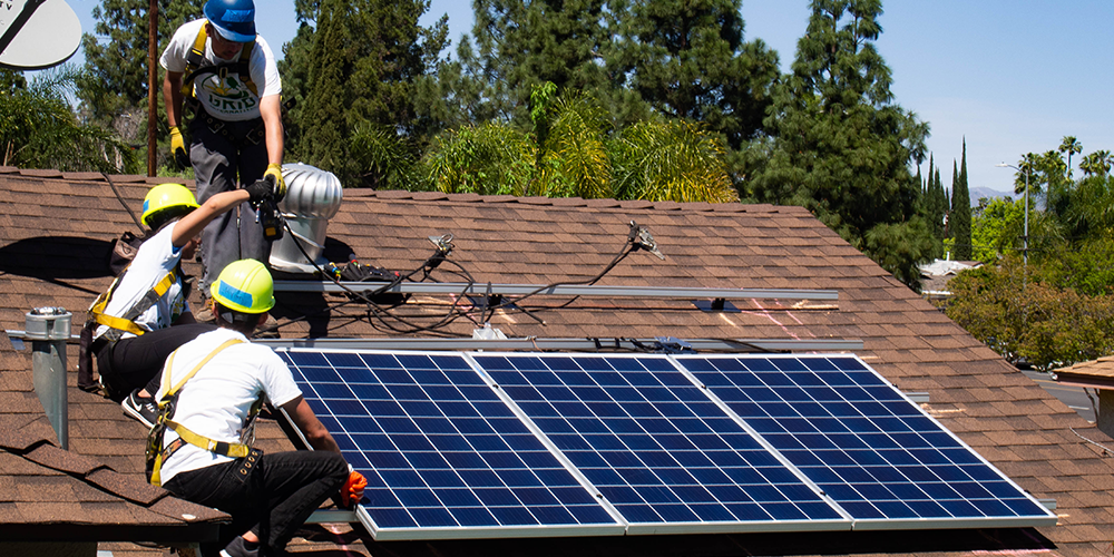 Trainees from GRID Alternatives install solar panels on a roof in Los Angeles.