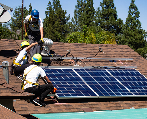 Trainees from GRID Alternatives install solar panels on a roof in Los Angeles.