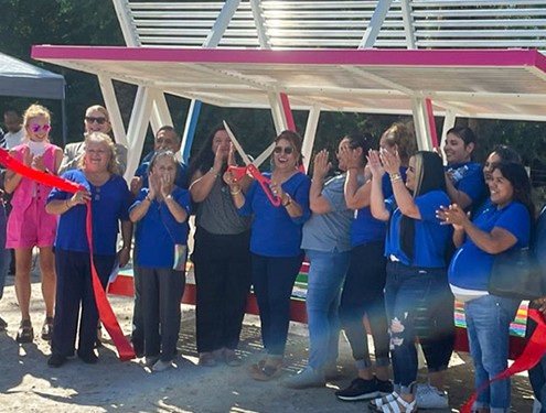 Collaborators celebrate the unveiling of a new bus shelter in Oasis, California