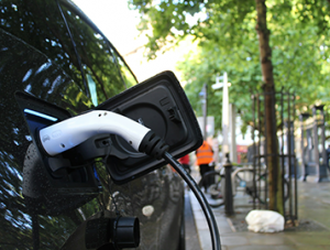 A black electric vehicle plugged into a charger