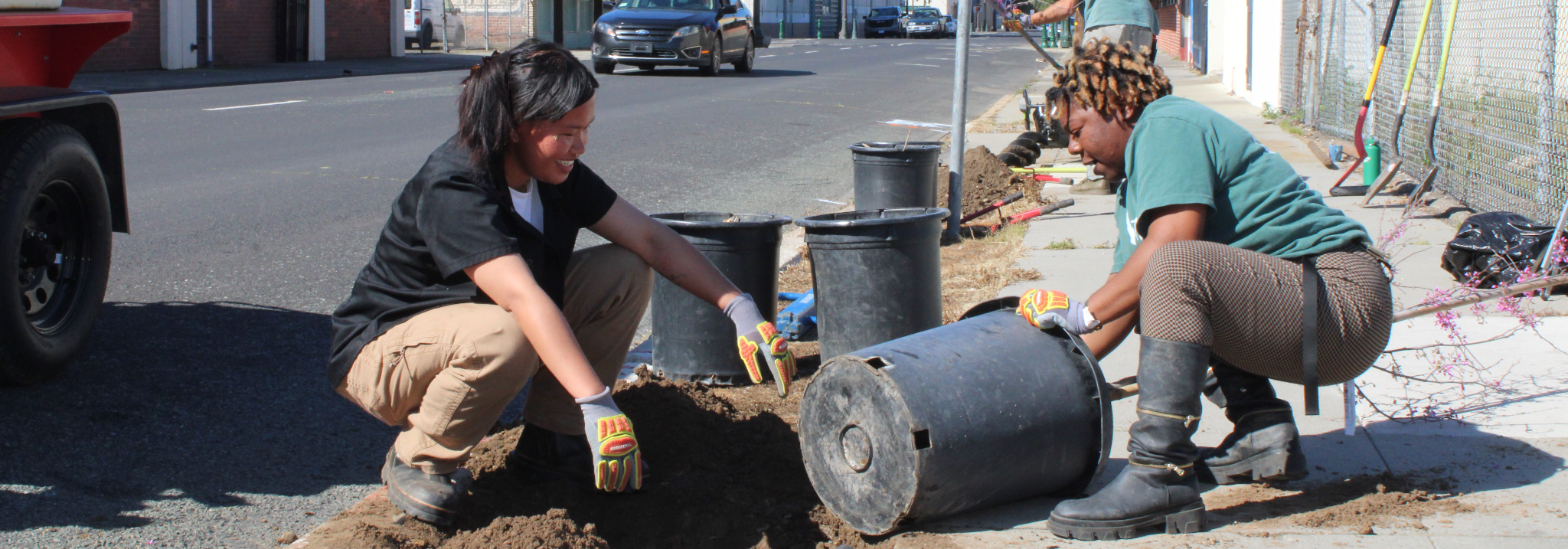Glenabel Toreno and Venecia Johnson prepare a tree for planting along a sidewalk in the Stockton Rising project area