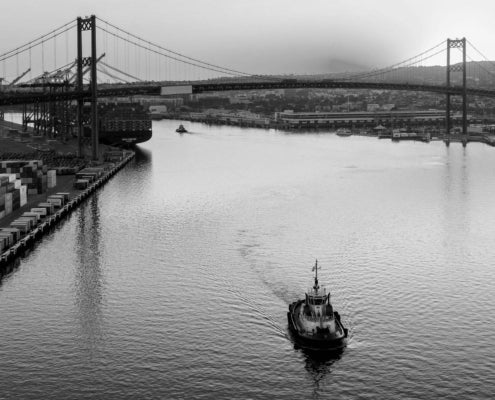 A boat is on the water in front of a bridge.