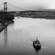 A boat is on the water in front of a bridge.