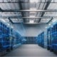 Server room with rows of illuminated computer servers, overhead ventilation ducts and blue digital light effects.